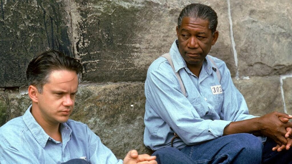Cena do filme Um Sonho de Liberdade com dois prisioneiros conversando, simbolizando amizade e esperança.